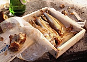 Smoked fish in a wooden box in front of a beer bottle