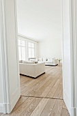 Moderner heller Wohnraum mit weißem Sofa und Holzboden, Fensterfront und Flügeltür