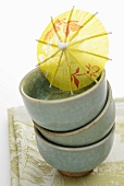Three Asian bowls and a cocktail umbrella
