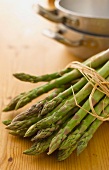 A bundle of asparagus with cooking equipment in the background