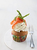 A cupcake topped with cream cheese, wild asparagus, salmon and black pepper