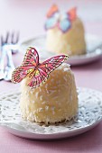 White marshmallow kiss decorated with grated coconut and with a butterfly made from edible paper