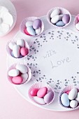 Sugared almonds in muffin cases on a plate with a message of love, for a wedding