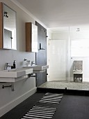 Zwei Waschbecken unter Spiegelschränken und abgetrennter, verglaster Duschbereich in modernem Ambiente