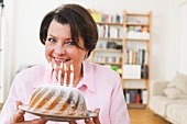 A middle-aged woman holding a birthday cake