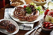 A plate of barbecued sausage spirals and sausages