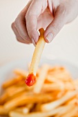 Frauenhand hält Pommes frites mit Ketchup