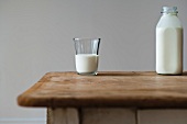 Milchglas und Milchflasche auf Holztisch