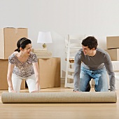 Couple unrolling rug in new house