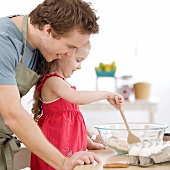 Father and daughter mixing batter in kitchen
