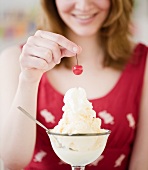 Woman putting a cherry on top of ice cream