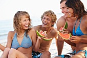 Young couples eating watermelon on beach