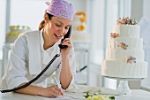 Happy young woman taking order near wedding cake
