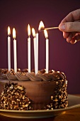 Studio shot of man igniting candles on chocolate birthday cake
