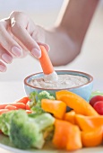 USA, New Jersey, Jersey City, Close-up view of woman hand putting baby carrot into dip