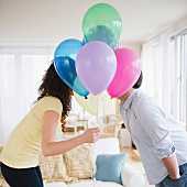 Pärchen küsst sich hinter vorgehaltenen Luftballons