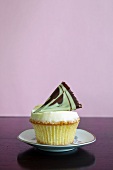 A cupcake topped with a fan of chocolate and pistachio