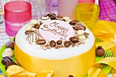 Birthday cake with chocolate candies and yellow bow