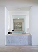 Badewanne mit Marmor Seitenwand in offene Nische eingebaut und raumhoher Spiegel gegenüber an Wand