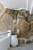 White urn in corner of terrace against whitewashed stone balustrade and rock wall