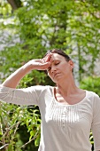Frau mit Kopfschmerzen im Garten