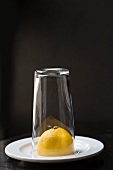 Half a lemon under a glass on a white plate