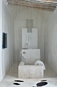 Fine bead curtain in front of stone bathtub in recess with wood-beamed ceiling