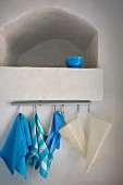 Blue bowl in limewashed niche; tea towels and bags hanging from hooks