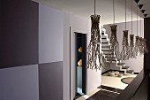 Künstlerisch gestaltete Schirme von Hängeleuchten in grau getönten Gangbereich und Blick ins Treppenhaus