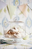 Vanilla meringues under a glass cloche at a buffet