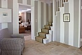 Walls with wide stripes and stone flags in classic foyer with foot of stairs