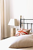 Stylised Union Flag cushion on metal bed and bedside lamp with rustic wooden base