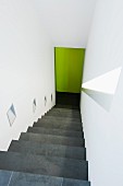 Steep staircase in white stairwell with sconce lamps integrated in wall