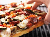 Sausage, vegetable and mozzarella pizza cooked on the barbecue