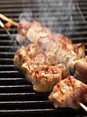 Barbecued skewers of pork wrapped in bacon