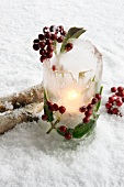 Windlicht aus Eis mit Ilexbeeren im Schnee