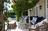 Large terrace with climber-covered pergola above rattan furniture outside traditional country house