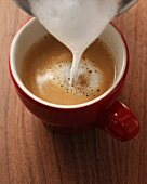 Milk foam being poured onto espresso