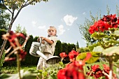 Germany, Bavaria, Boy watering garden flowers