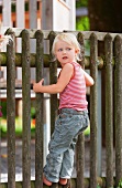 Mädchen steht auf dem Zaun am Spielplatz