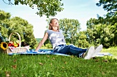 Germany, Cologne, Young woman relaxing at picnic
