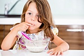 Germany, Girl eating muesli in kitchen