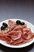 Slices of salami with olives on a plate