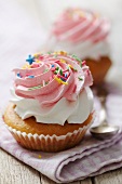 Cupcake with cream, raspberry cream and colorful sugar sprinkles