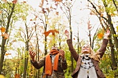 Couple playing with autumn leaves in woodland