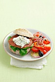 A burger topped with tzatziki, served with Greek salad