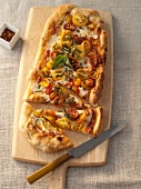 Margherita Pizza with Yellow and Red Tomatoes and Fresh Basil; Sliced on a Cutting Board
