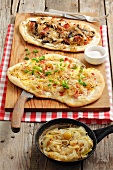 Two tarte flambées (one with sauerkraut, mushrooms and bacon and one with onions, cheese and bacon)