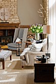 Wood-burning stove in open fireplace with brick chimney breast behind checked grey reading chair; magnificent summer bouquet in corner