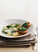 Clear broth with tortellini and spinach, served with pesto on toast
